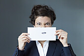 Portrait of mid adult woman holding paper with zigzag sign, close-up