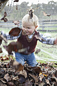 Baby boy throwing dry leaves