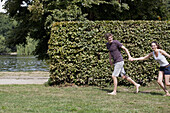 Young couple holding hands and running in park