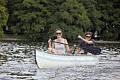 Young couple riding paddle boat on lake