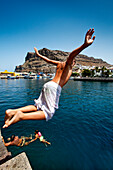 Boy jumping in the sea, Puerto de Mogan, Gran Canaria, Canary Islands, Spain