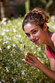Young woman enjoying the smell of fragrant of jasmine flowers, Seville, Andalusia, Spain