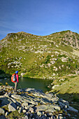 Woman hiking looking towards mountain lake Lago delle Trote, lake lago delle Trote, Trans-Lagorai, Lagorai range, Dolomites, UNESCO World Heritage Site Dolomites, Trentino, Italy