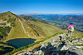 Woman looking towards Wildseeloder, lake Wildsee and Kaiser range while hiking, Henne, Kitzbuehel range, Tyrol, Austria