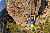 Frau klettert an roten Granitfelsen, Mottarone, Piemont, Italien