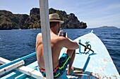 Young man with mobile phone on a boat in the Archipelago Bacuit near El Nido, Palawan Island, South China Sea, Philippines, Asia
