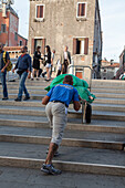 Arbeiter mit Sackkarre, Transport und Entladen, Transport von Hotelwäsche über die Treppen der Brücken, Venedig, Italien