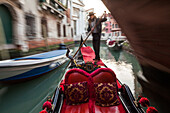 tourist trip on gondola in a narrow canal in historic Castello, art of rowing, gondolier, below bridge in narrow canal romantic, blurred, moving, Venice, Veneto, Italy