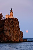 Split Rock Lighthouse in the last light of the day as a full moon rises over Lake Superior at Split Rock Lighthouse State Park on the north shore of Lake Superior in Minnesota.