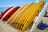 Surfboards Of Different Lengths And Colors Lined Up On A Rack
