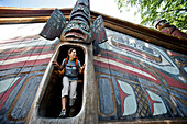 Woman Explores The Clan House At Totem Bight State Historical Park Near Ketchikan, Southeast Alaska, Summer