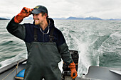 'Commercial halibut fishing by hand using longline gear out of an open skiff in Kachemak Bay, Kenai Peninsula; Alaska, United States of America'