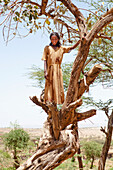 'Portrait of a young girl standing in a tree; Ethiopia'