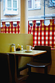 'A restaurant with red and white checkered curtains on the window and a yellow wall; London, England'