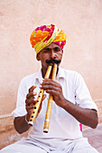 'A man playing a musical instrument at Ranvas Palace; Rajasthan, India'
