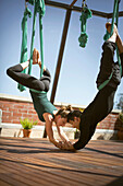 Ein schönes Mädchen und ein junger Mann machen Aerial Yoga in San Diego, Kalifornien.