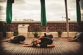 Drei junge Frauen und ein junger Mann machen Aerial Yoga.