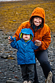 Portrait of mom and son on a rainy beach that is blanketed in kelp in Seward, Alaska.