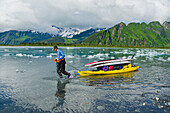 Man hauls SUPs and gear on a kayak up the feeder river to Bear Lake and Bear Glacier, Alaska.