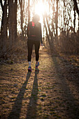 A woman out for a walk through a wooded trail.