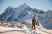 A skier crosses a snowfield with Mount Shuksan in the background during a winter ski tour.
