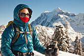 Portrait of a woman with winter clothes on while snowshoeing. Mount Shuksan can be seen in the background.