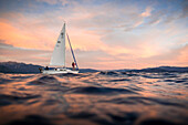 Clint Celio (skipper) and Sabina Allemann (crew) sail the small yacht Freshwater Cowboy on Lake Tahoe at sunset.