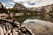 Boy sitting on a tree trunk at the edge of a mountain lake in Mammoth Lakes, California.