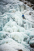 Man lead climbing an ice fall in the middle of a snow storm in Argenti?®re, Chamonix, France.