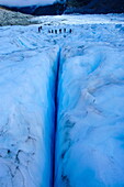 Tourists hiking above a giant crack on Fox Glacier, Westland Tai Poutini National Park, South Island, New Zealand, Pacific
