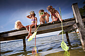 Girls with dip nets sitting on jetty at lake Starnberg, Upper Bavaria, Bavaria, Germany