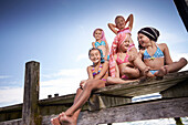 Girls sitting on a jetty, hairs wrapped in towels, lake Starnberg, Upper Bavaria, Bavaria, Germany