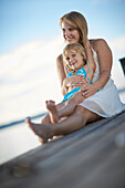 Mutter und Tochter sitzen auf einem Steg am Starnberger See, Oberbayern, Bayern, Deutschland