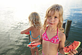 Two girls eating slices of melon, lake Starnberg, Upper Bavaria, Bavaria, Germany