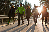 Five young people walking along a street, Grosser Alpsee, Immenstadt, Bavaria, Germany