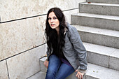 Young woman sitting on a staircase looking at camera, Munich, Bavaria, Germany