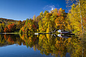 Cottages and fall foliage color in the trees reflected in a calm lake at La Beauport, Quebec, Canada.