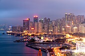 Skyline of Hong Kong Island with commercial and residential buildings with a conjested road in the foreground at dusk, China, East Asia
