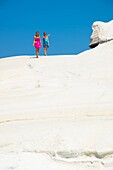 two teens walking on the white sandstone cliffs of Sarakiniko beach at milos, Greece