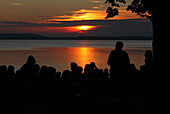 People in the evening at lake Chiemsee, Chieming, Bavaria, Germany