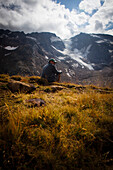 Man sitting on a mountain meadow, rear of Gschnitz Valley (ca. 2413 m), Stubai Alps, Tyrol, Austria