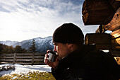 Hiker taking a rest and drinking out of a cup, Koegl alp (1432 m), descent from Unnutz Mountain (2078 m), Rofan Mountains, Tyrol, Austria
