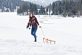 Young woman pulling a sled, Spitzingsee, Upper Bavaria, Germany