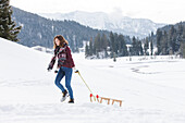Young woman pulling a sled, Spitzingsee, Upper Bavaria, Germany