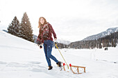Young woman pulling a sled, near Spitzingsee, Upper Bavaria, Germany