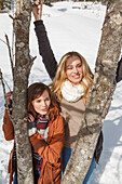 Two young women between tree trunks, Spitzingsee, Upper Bavaria, Germany