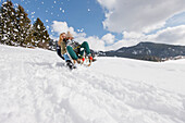 Two young women downhill sledding, Spitzingsee, Upper Bavaria, Germany