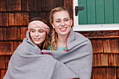 Two young women wrapped in a blanket, Spitzingsee, Upper Bavaria, Germany