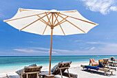 Tourists sunbathing on sun loungers at white sandy beach, Gili Air, Lombok, Indonesia