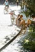 Teenage girls cooling their feet in a stream, Freiburg im Breisgau, Black Forest, Baden-Wuerttemberg, Germany